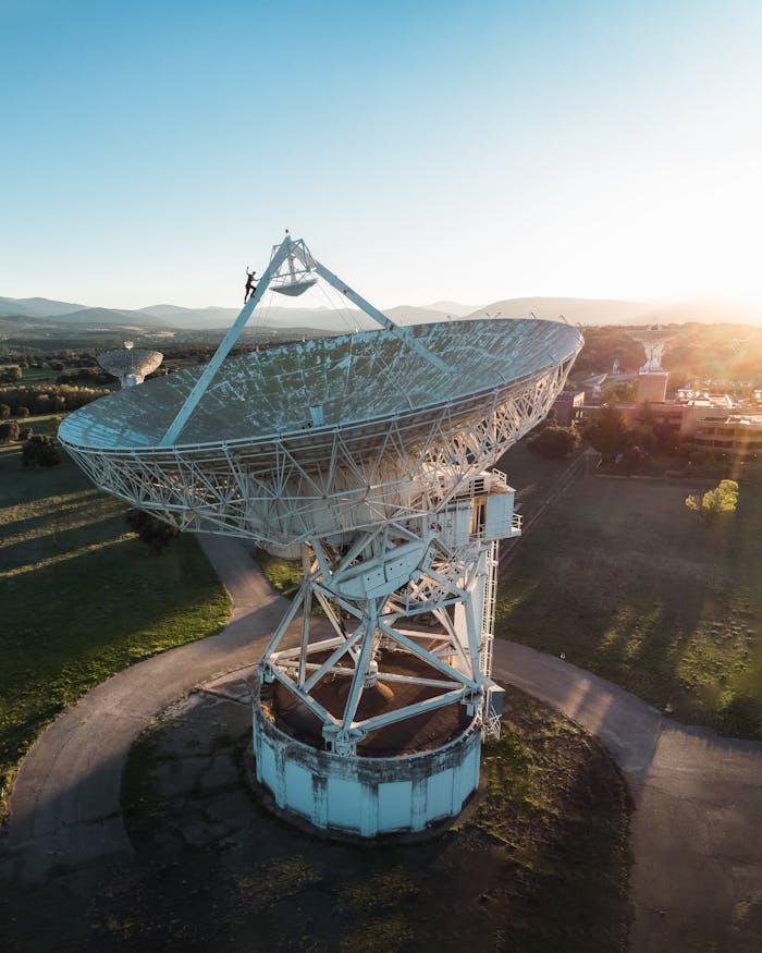 A towering satellite dish in a field at sunrise, highlighting technology and exploration.