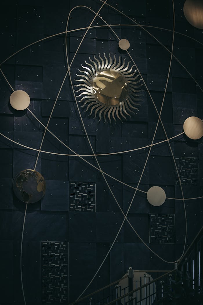 A dark cosmic-themed installation with metallic sun and planets in orbital paths.